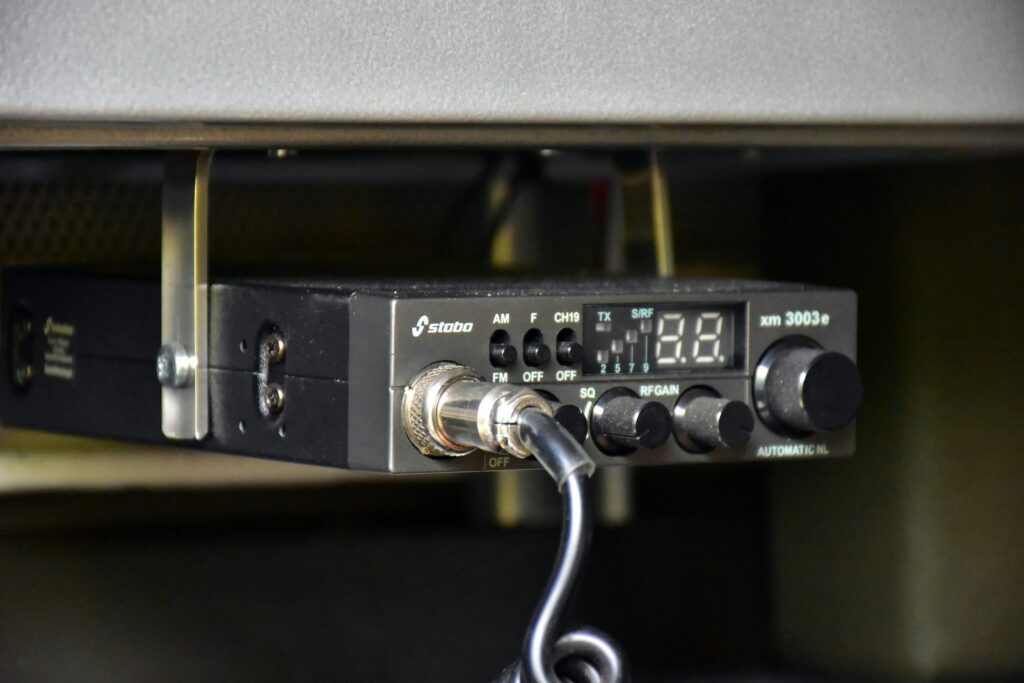 Un poste radio à boutons et afficheur, fixé sous une tablette.