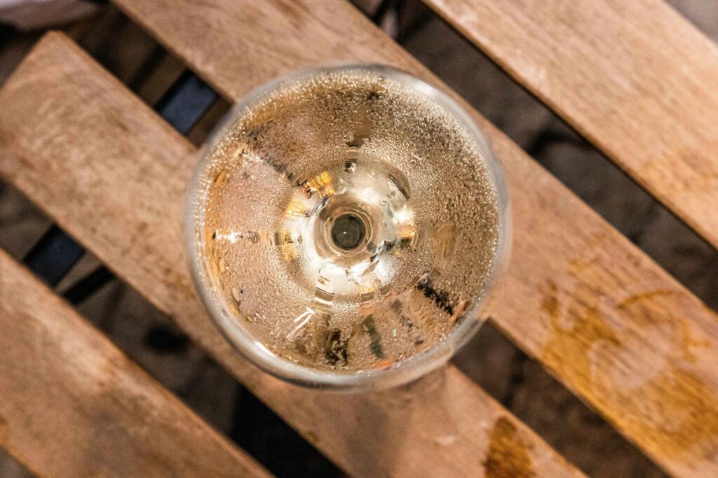 Un verre de boisson pétillante posé sur une palette de bois.