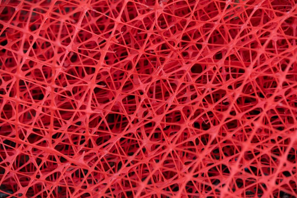 Gros plan sur un enchevêtrement de filaments de plastique rouge.