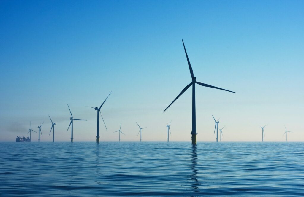 Éoliennes en mer alignées sur une mer calme, sous un ciel dégagé.