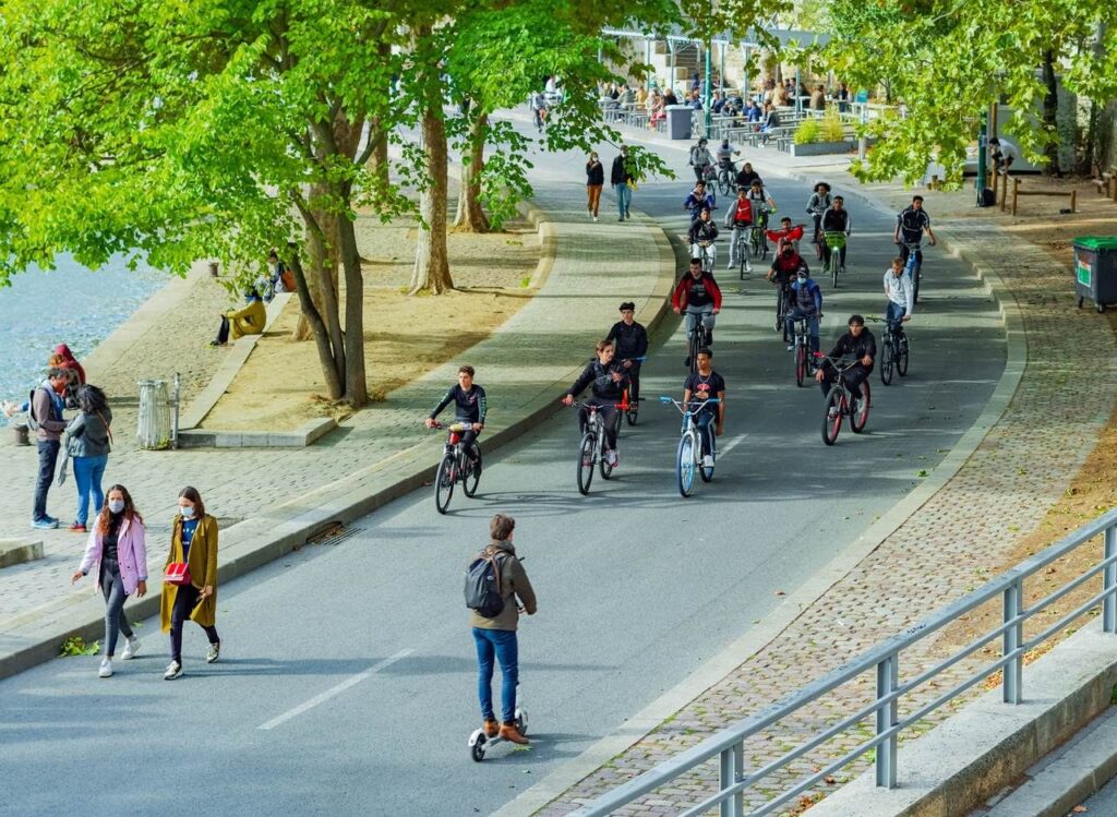 Cyclistes et promeneurs sur une voie verte bordée d'arbres.