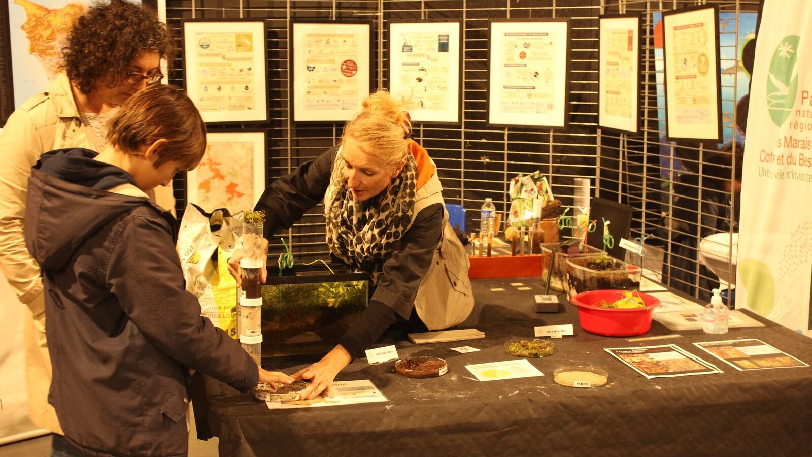 Des visiteurs manipulent des échantillons de sol sur un stand documenté de panneaux.