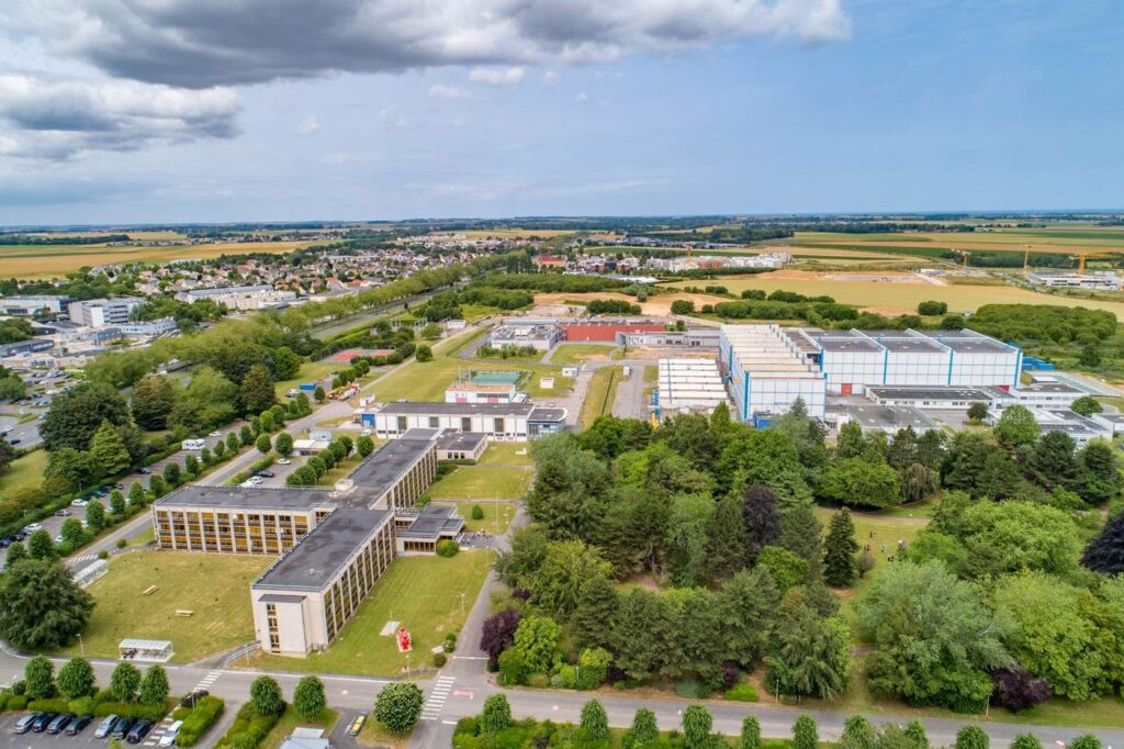 Vue aérienne d'un site de recherche : bâtiments blancs entourés d'arbres et de champs.