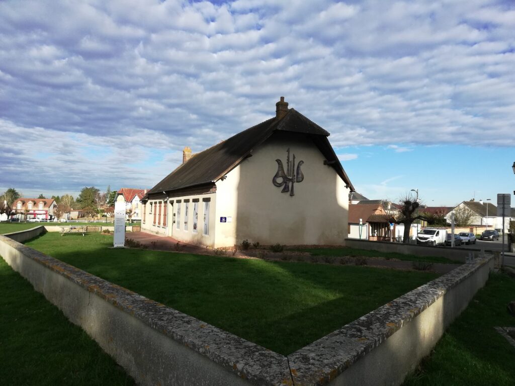 Bâtiment de musée à colombages et toit de chaume, entouré de pelouse.