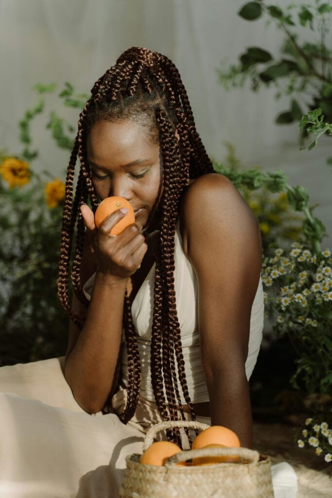 Une personne sent un abricot au-dessus d'un panier de fruits.