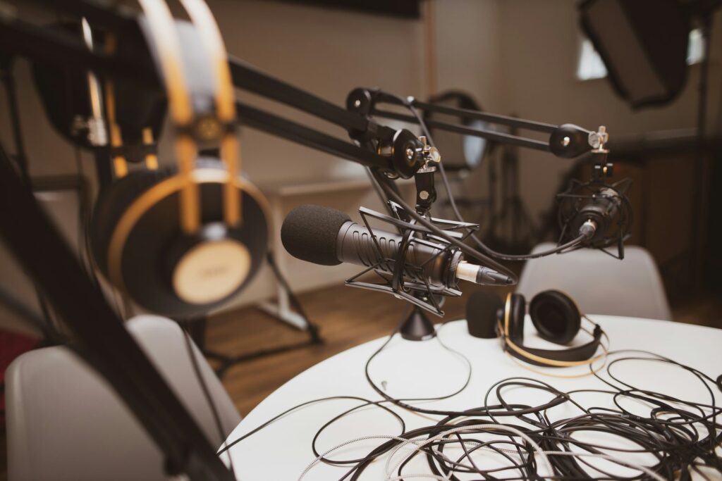 Micro de studio sur pied articulé et casque posé sur une table d'enregistrement.