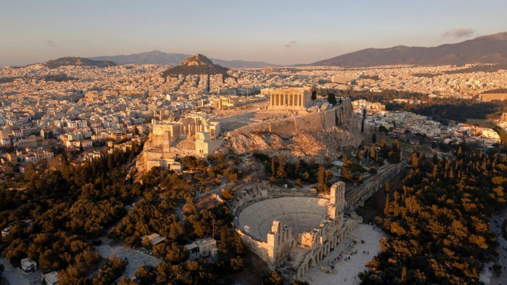 Vue aérienne d'Athènes au coucher du soleil, avec l'Acropole au premier plan.