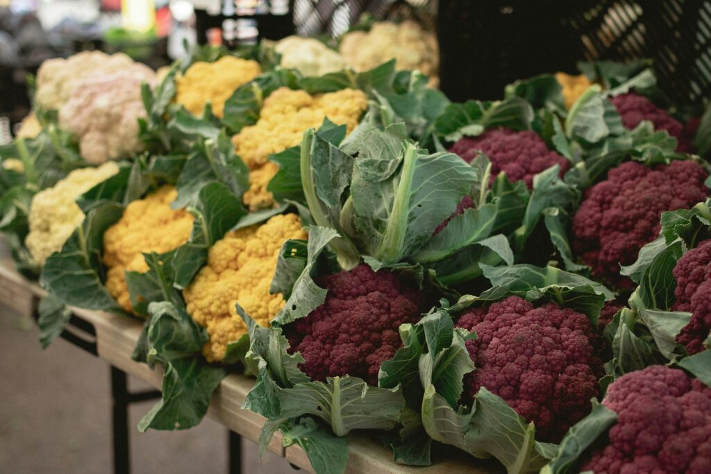 Choux-fleurs blancs, jaunes et violets présentés sur un étal.