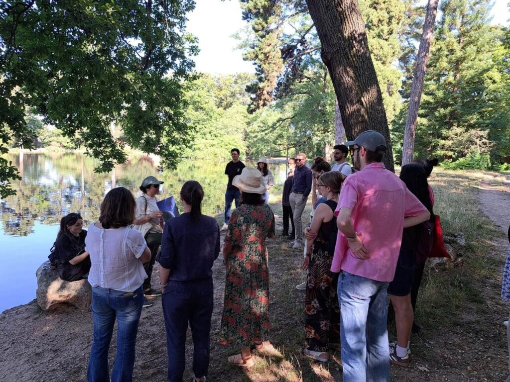 Un groupe de visiteurs réunis autour d'un médiateur au bord d'un plan d'eau.