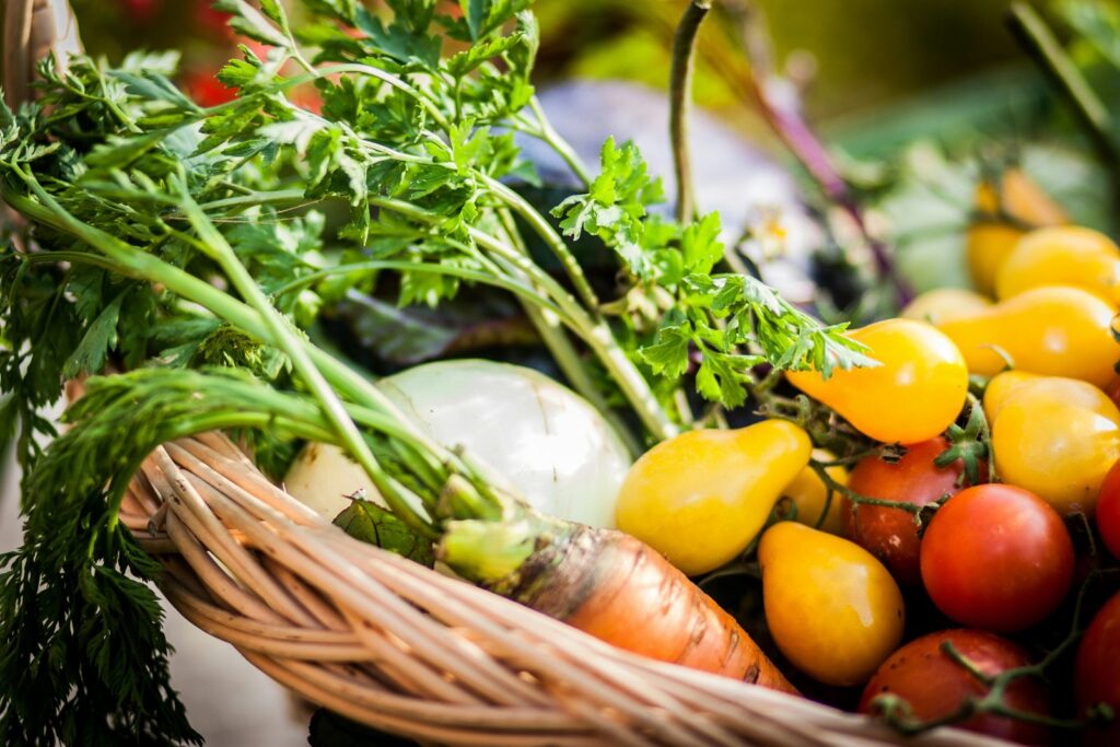 Panier d'osier rempli de légumes et d'herbes fraîches.