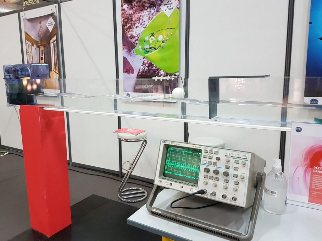 Oscilloscope et canal hydrodynamique installés sur un stand d'expériences.