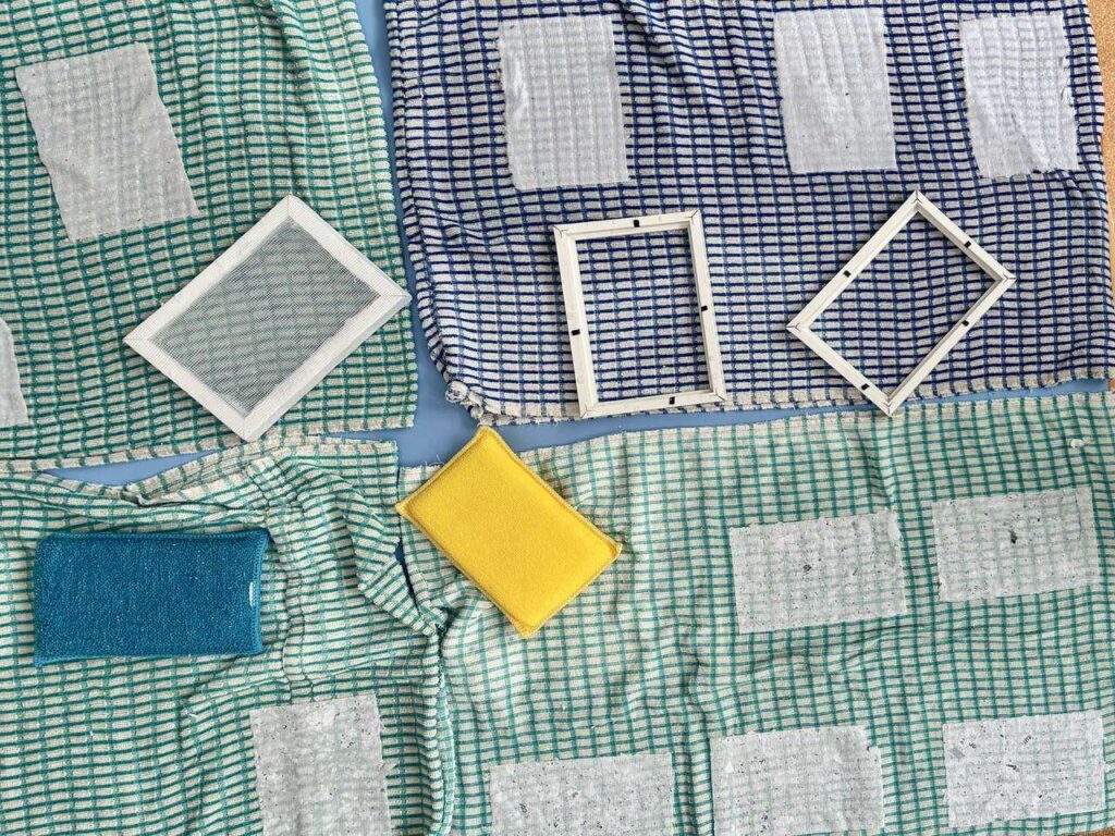 Feuilles de papier recyclé posées à sécher sur une toile à carreaux.