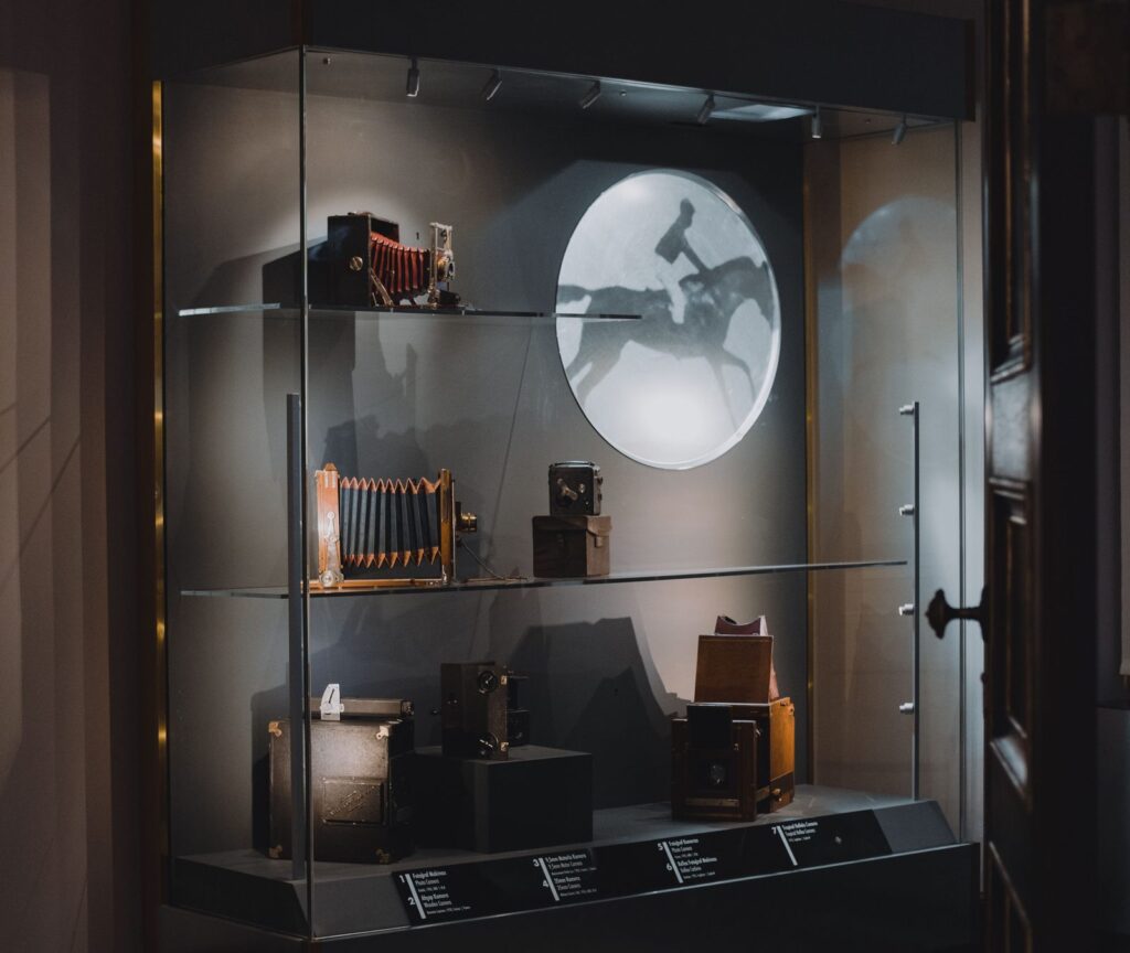 Vitrine de musée présentant des appareils de projection et de photographie anciens.