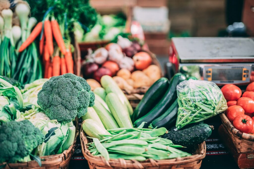 Étal de légumes : carottes, brocolis, courgettes et tomates dans des paniers.