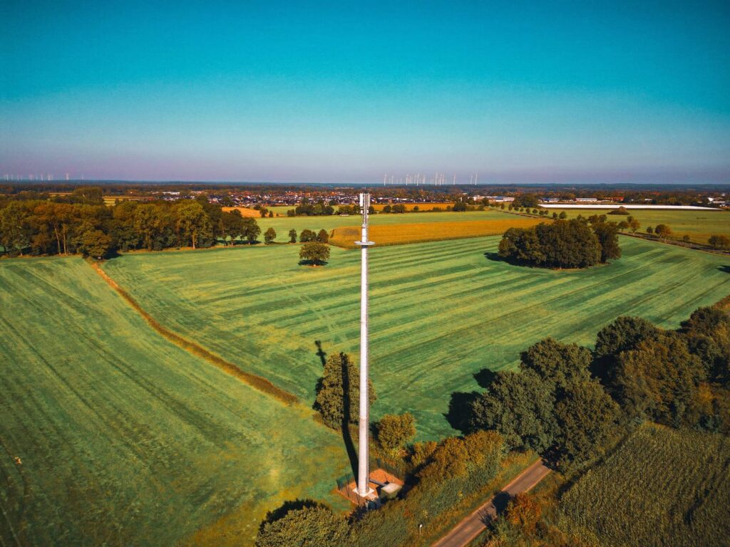 Vue aérienne d'un pylône de télécommunication au milieu de champs cultivés.
