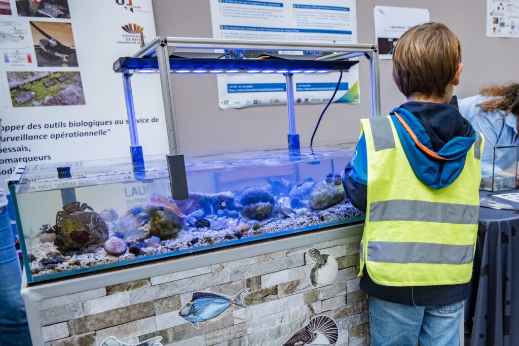 Visiteurs observant une expérience scientifique, lors d une précédente Fête de la science.