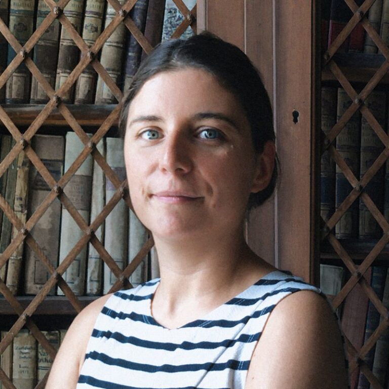 Portrait de Lucie Planty, artiste et doctorante, devant une bibliothèque ancienne.
